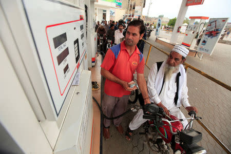 Motorcyclists wait in line as an attendant fiils the tank of a motorcycle at a petrol station in Rawalpindi, Pakistan July 26, 2017. REUTERS/Faisal Mahmood