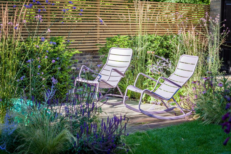 Verbena bonariensis and Salvia caradonna, along with ornamental grasses, fringe a seating area in a London garden designed by Barbara Samitier