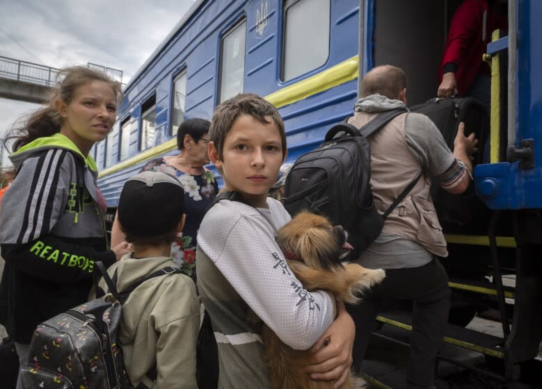 A boy holds his pet dog as his family evacuated from the war-hit area.