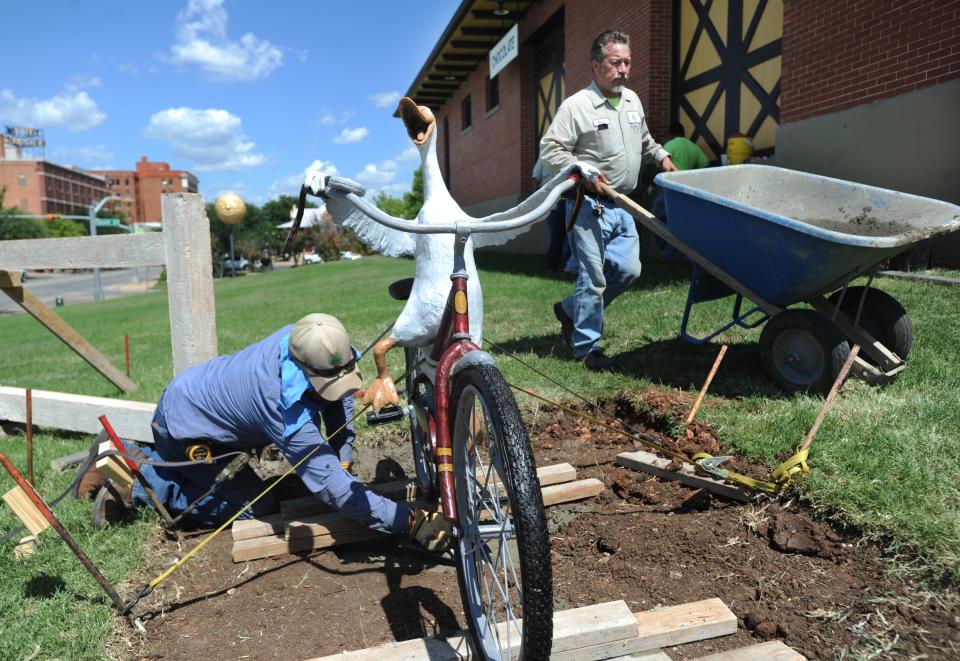 City of Abilene workers pour concrete at the base of the Duck on a Bike statue by Candies by Vleta's.