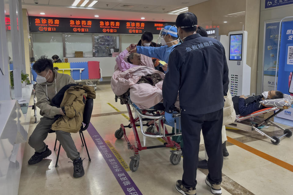 A medical worker checks on an elderly woman on a stretcher at the emergency ward of a hospital in Beijing, Thursday, Jan. 5, 2023. Patients, most of them elderly, are lying on stretchers in hallways and taking oxygen while sitting in wheelchairs as COVID-19 surges in China's capital Beijing. (AP Photo/Andy Wong)