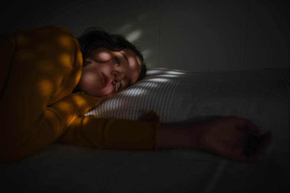 A kid lying in bed in the dark