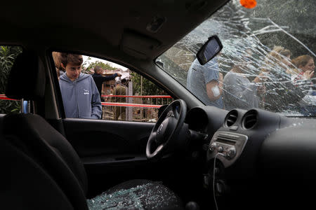 An Israeli boy looks into a damaged car next to a house that was hit by a rocket north of Tel Aviv Israel March 25, 2019. REUTERS/ Ammar Awad