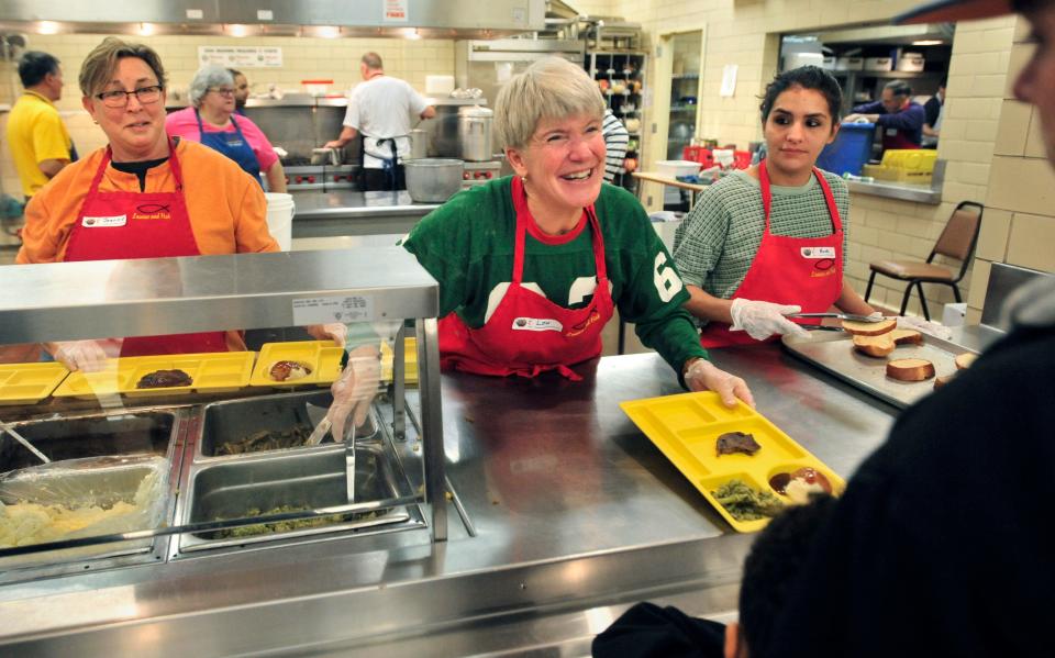 Volunteers Lou Dobrydnia, middle, Jeannie Jones, left, and Nicole Leal, all of Peoria, dish out a little fellowship with the food during the Loaves & Fish Ministry's Christmas meal in 2015 at First United Methodist Church in Downtown Peoria.