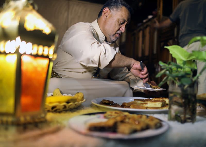 Akram al-Kebsi serves dessert dishes of rawani and baklava for guests after the iftar meal during the holy month of Ramadan at his home in Sanaa