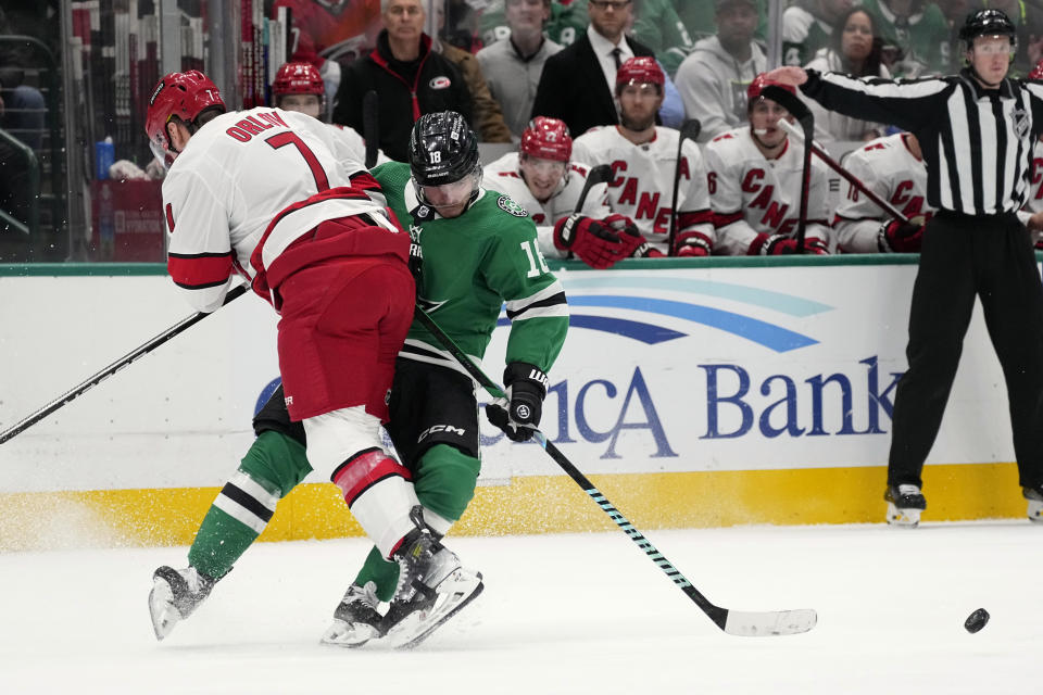 Dallas Stars center Sam Steel (18) loses control of the puck as he takes a hard hit from Carolina Hurricanes defenseman Dmitry Orlov (7) in the first period of an NHL hockey game in Dallas, Tuesday, Feb. 13, 2024. (AP Photo/Tony Gutierrez)