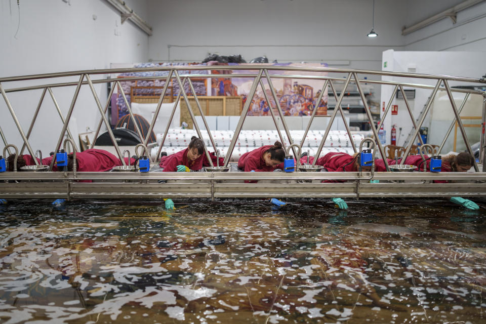 Staff workers clean a tapestry at the Royal Tapestry Factory in Madrid, Spain, Friday, Nov. 30, 2023. Since its foundation in 1721, the Royal Tapestry Factory of Madrid has not stopped producing. It was Philip V, then King of Spain, who had the factory built with the help of Catholic craftsmen from Flanders to replace the lack of private initiative that existed at the time. (AP Photo/Manu Fernandez)