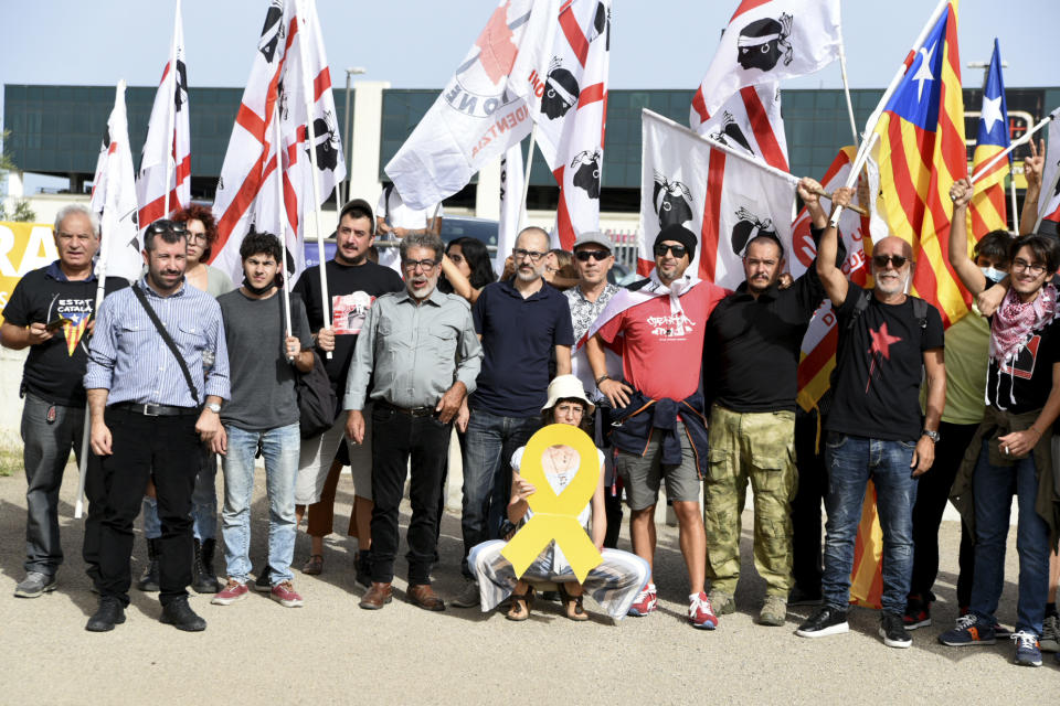 Demonstrators hold Sardinian and Catalonian, right, flags as they stand outside a court in Sassari, in Sardinia, Italy, Friday, Sept. 24, 2021. Former Catalan leader Carles Puigdemont, sought by Spain for a failed 2017 secession bid, on Friday awaited his opportunity to appear in court to argue against extradition, a day after Italian police detained him in Sardinia, an Italian island with strong Catalan cultural roots and its own independence movement. (AP Photo/Gloria Calvi)