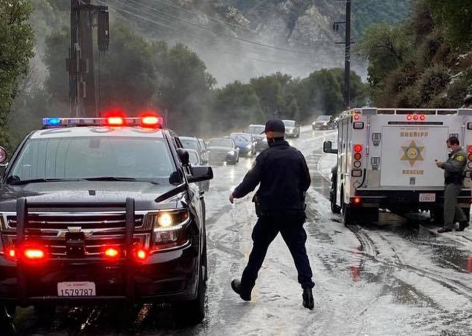 In this Saturday, Jan. 23, 2021, photo provided by the California Highway Patrol-West Valley, authorities work the scene of an accident after a hail storm on Malibu Canyon Road in Malibu, Calif. A hail storm struck the Santa Monica Mountains on Saturday, prompting the California Highway Patrol to warn drivers to slow down after officers responded to a few rollover accidents on Malibu Canyon. Up to a foot of snow fell in Southern California's mountains as the first in a series of storms move through California, bringing real winter weather after weeks of sporadic rain that has done little to ease drought. (California Highway Patrol via AP)