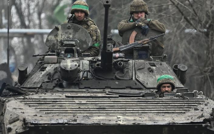 Ukrainian servicemen ride on a BMP infantry fighting vehicle on a road near Bakhmut - GENYA SAVILOV/AFP
