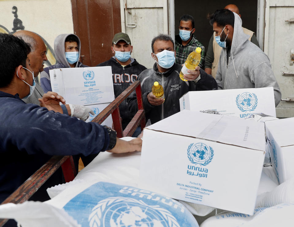 Palestinian workers load food supplies distributed by the United Nations Relief and Works Agency (UNRWA) at the Sheikh Redwan neighborhood of Gaza City, Tuesday, March 31, 2020. The United Nations has resumed food deliveries to thousands of impoverished families in the Gaza Strip after a three-week delay caused by fears of the coronavirus. UNRWA, provides staples like flour, rice, oil and canned foods to roughly half of Gaza’s 2 million people. (AP Photo/Adel Hana)