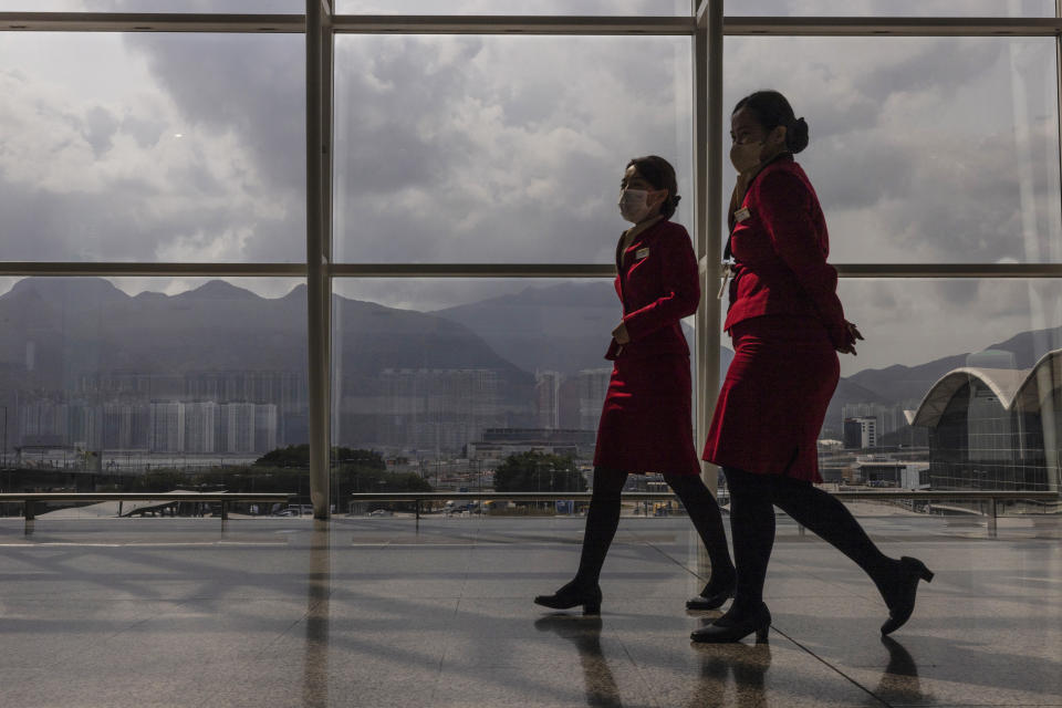 Cathay Pacific Airways employees walk through the departures hall of Hong Kong International Airport in Hong Kong, on Wednesday, March. 8, 2023. Cathay Pacific Airways Ltd. said it was ready to rebuild as Hong Kong opened up to global visitors, despite reporting wider losses in 2022. (AP Photo/Louise Delmotte)