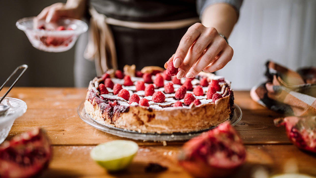 Woman Putting Raspberries To American Blackberry Pie, While It Is In  Mold.