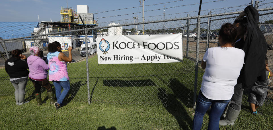Friends, coworkers and family watch as U.S. immigration officials raid several Mississippi food processing plants, including this Koch Foods Inc., plant in Morton, Miss., Wednesday, Aug. 7, 2019. The early morning raids were part of a large-scale operation targeting owners as well as undocumented employees. (AP Photo/Rogelio V. Solis)