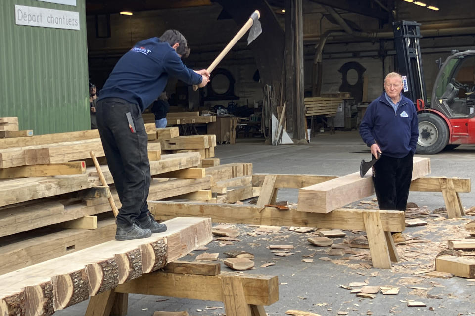 A carpenter uses an axe to cut a wooden beam for the new roof of the Notre Dame de Paris cathedral, Thursday, May, 25, 2023, near Angers, western France. Carpenters building a new timber frame for the fire-ravaged roof of Paris' Notre Dame Cathedral are using the same tools and techniques as their medieval predecessors. For them, working with hand-axes to fashion oak beams has been like stepping back in time. (AP Photo/Jeffrey Schaeffer)