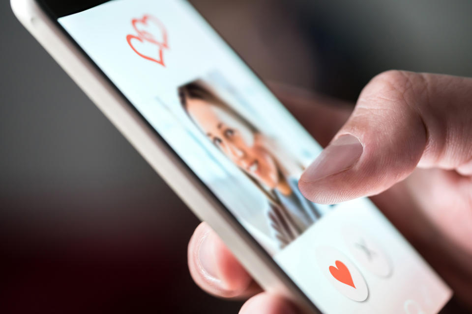 A man uses a dating app on a smartphone.