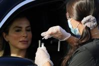 A healthcare worker performs a COVID-19 test at a drive-thru testing center Tuesday, Dec. 8, 2020, in Phoenix. Arizona on Tuesday set a new daily record with over 12,300 additional known coronavirus cases as the number of hospitalized patients approached levels similar to the peak of last summer's surge, with the state's seven-day rolling average continuing to climb in the past two weeks as have the rolling averages for daily deaths and daily COVID-19 testing positivity. (AP Photo/Ross D. Franklin)