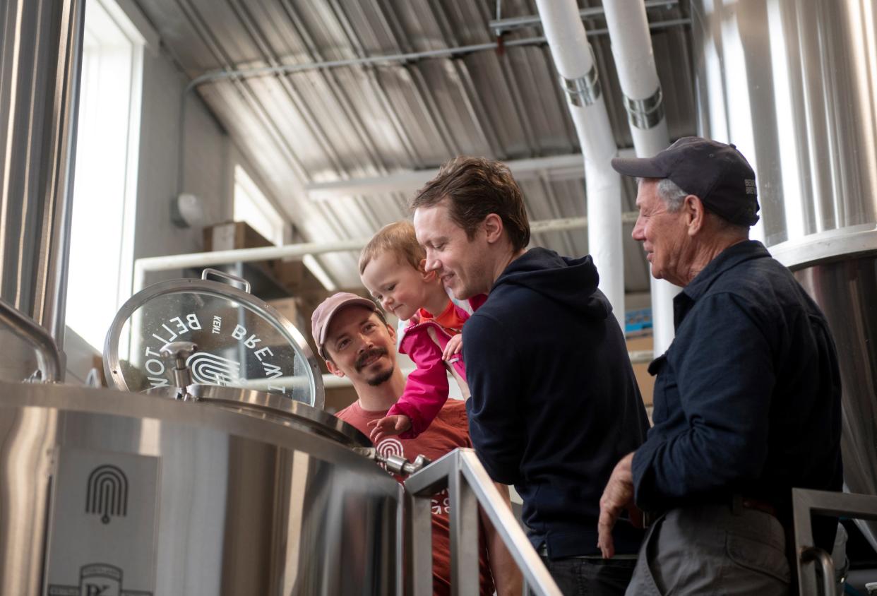 Benjamin Tipton, Seth Tipton, holding his daughter Remy, 2, and Chuck Tipton, look at the progress in the second kettle of a beer brewed for Father's Day at Bell Tower Brewing Co. in Kent.