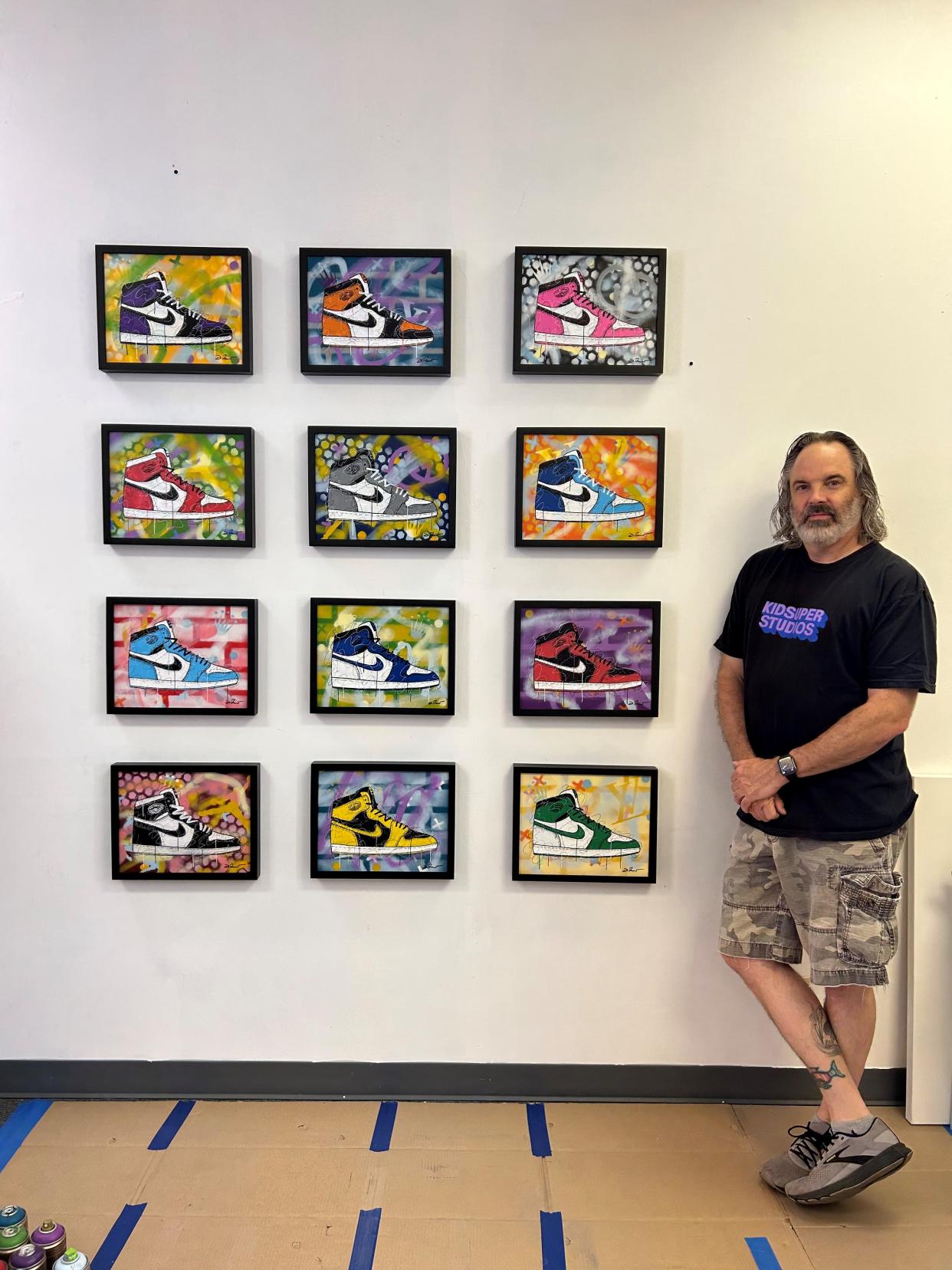St. Louis-based graffiti pop artist David Ruggeri poses beside a collection of his paintings featuring Jordan sneakers.