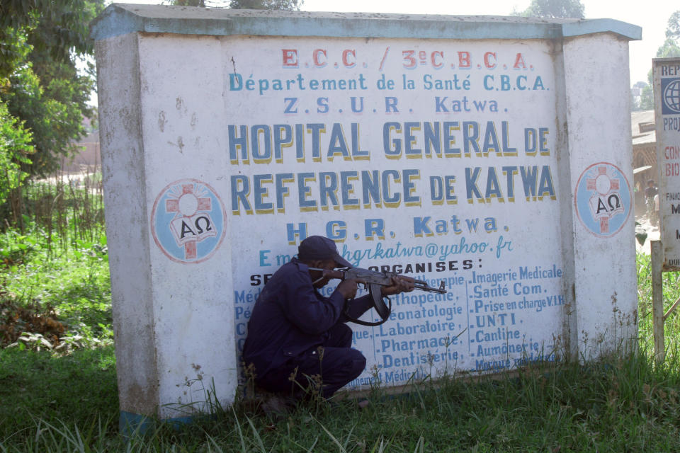Police shelter behind a hospital sign, as they guard a hospital in Butembo, Congo, on Saturday, April 20, 2019, after militia members attacked an Ebola treatment center in the city’s Katwa district overnight. Violence has deeply complicated efforts to contain what has become the second-deadliest Ebola virus outbreak in history. (AP Photo/Al-Hadji Kudra Maliro)