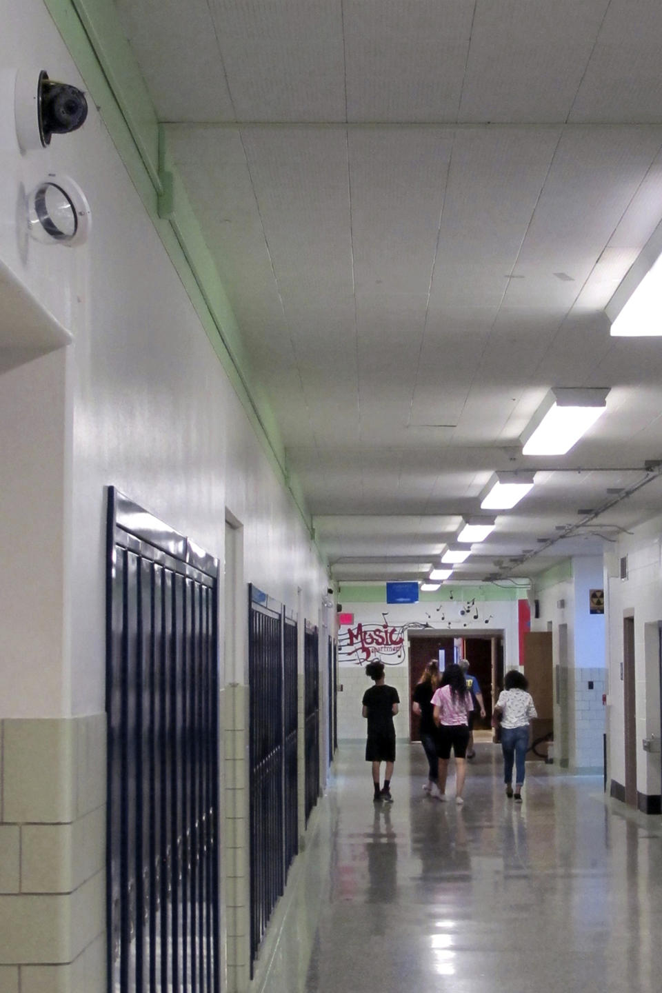 FILE - In this July 10, 2018 file photo, students walk down a hallway at Lockport High School in Lockport, N.Y., as a camera with facial recognition capabilities, upper left, hangs on the wall waiting for its installation to be completed. The New York Legislature has passed a two-year moratorium on the use of facial recognition in schools. The ban approved Wednesday, July 22, 2020, follows an upstate district's adoption of the technology as part of its security plans, and a lawsuit by civil rights advocates challenging the decision. (AP Photo/Carolyn Thompson, File)