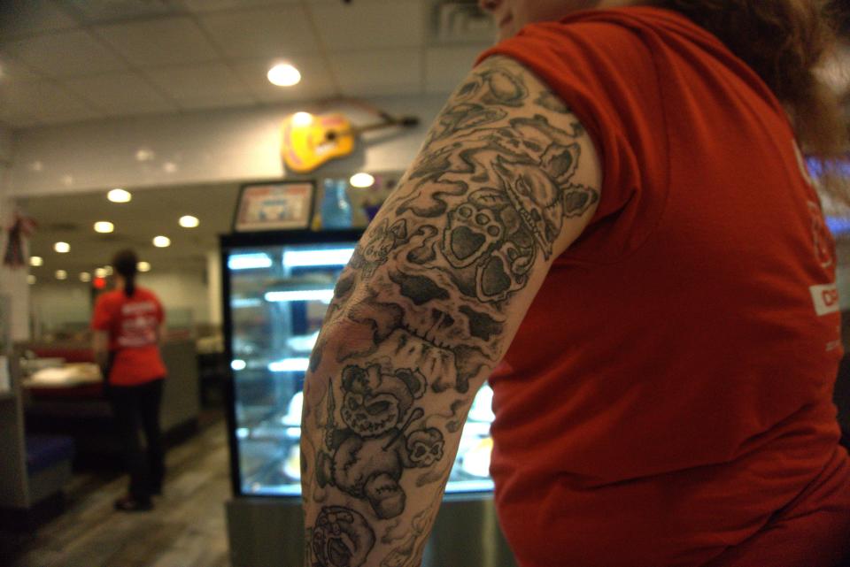 Kyra Taylor, a server at Round the Clock Diner shows off her vampire bunny voodoo tattoos displayed across her arm.