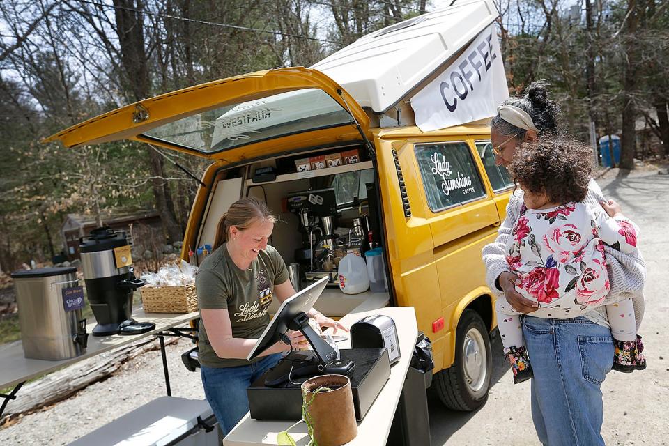 Elizabeth Estabrook sells coffee to Amina Ford, who is holding her daughter Aylah, 2, at the Lady Sunshine Coffee truck Wednesday.
