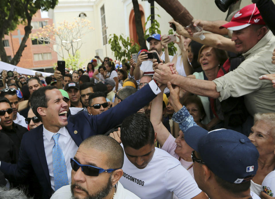 Juan Guaido, opposition leader and self-proclaimed interim president of Venezuela, greets supporters as he leaves Plaza Bolivar after an outdoor, town hall-style meeting in the Chacao area of Caracas, Venezuela, Friday, April 19, 2019. The opposition held the forum to announce a new strategy against the government of President Nicolas Maduro. (AP Photo/Fernando Llano)