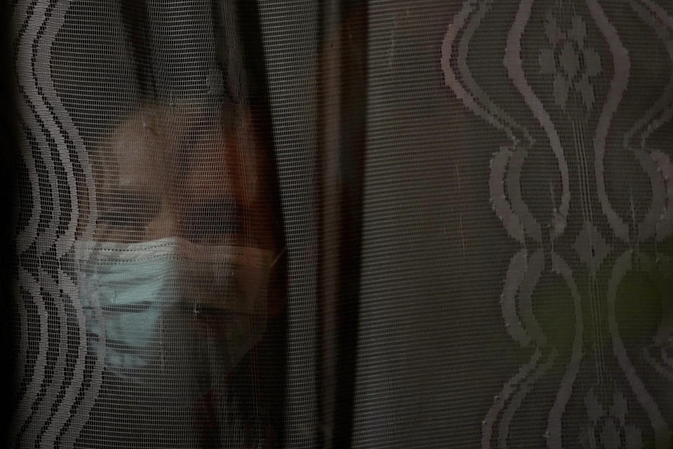 Natalicia Goncalves, a 77-year-old retired teacher, looks out from the window of her home in the Pinheiro neighborhood of Maceio, Alagoas state, Brazil, Sunday, March 6, 2022. Goncalves is the last remaining resident on her street after the others have been forced to leave because of the threat of ground subsidence and geological problems caused by the Braskem mine, that has caused the evacuation of more than 55 thousand people. (AP Photo/Eraldo Peres)