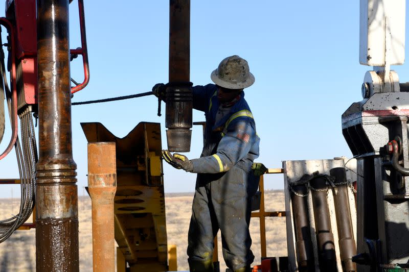 FILE PHOTO: An oil worker removes a thread cap from a piece of drill pipe near Midland, Texas