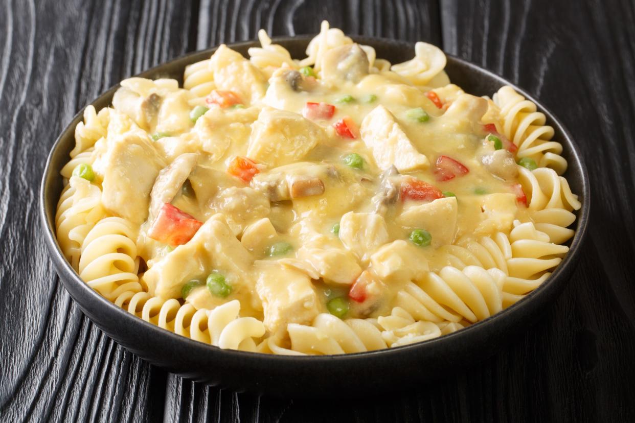 American food stewed chicken a la King in a creamy sauce with mushrooms served with pasta close-up in a plate on the table. horizontal