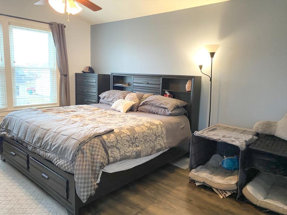 light blue walls, dark wood bed, bed in bedroom with dog cages next to it