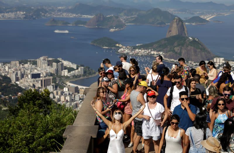 A tourist wearing a protective face mask poses for a photo during a visit to the statue of Christ the Redeemer after reports of coronavirus in Rio de Janeiro