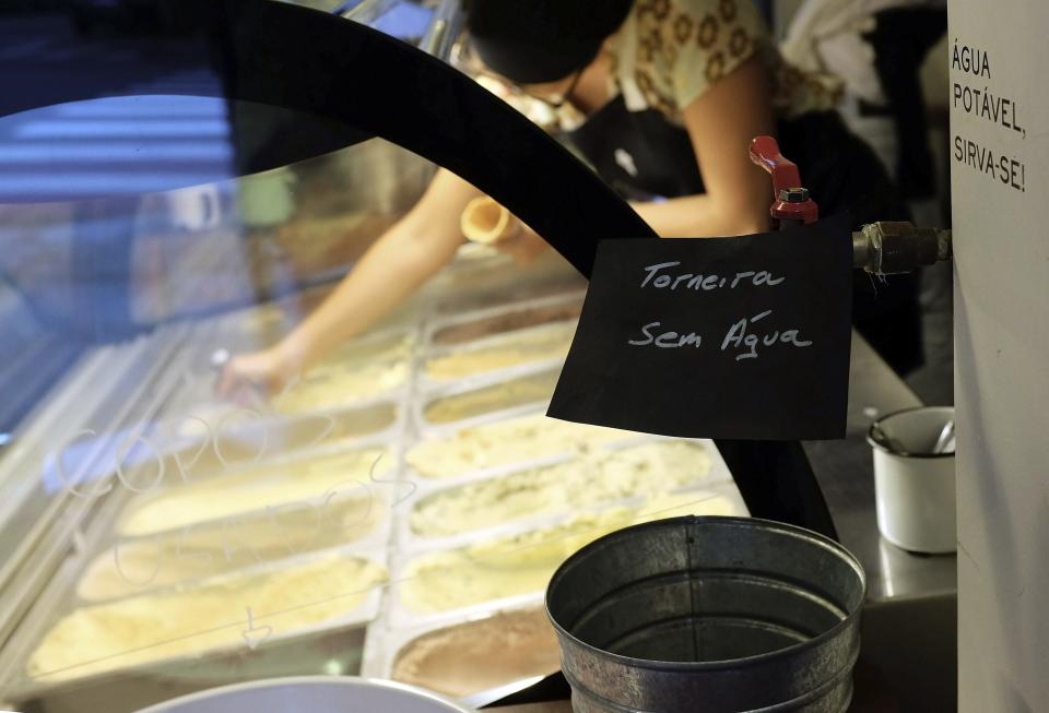 A sign (in black) that reads "Tap without Water" is seen inside an ice-cream shop at the Pinheiros neighbourhood in Sao Paulo February 10, 2015. Brazilians are hoarding water in their apartments, drilling homemade wells and taking other emergency measures to prepare for forced rationing that appears likely and could leave taps dry for up to five days a week because of a drought. In Sao Paulo, the country's largest city with a metropolitan area of 20 million people, the main reservoir is at just 6 percent of capacity with the peak of the rainy season now past. Many neighbourhoods have already experienced daily water outages as Sabesp turns down pressure in pipes to save consumption. Picture taken February 10, 2015. REUTERS/Nacho Doce (BRAZIL - Tags: DISASTER ENVIRONMENT SOCIETY)