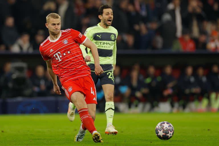 Matthijs de Ligt busca a un compañero mientras Bernardo Silva protesta detrás, en el partido entre Bayern Munich y Manchester City.