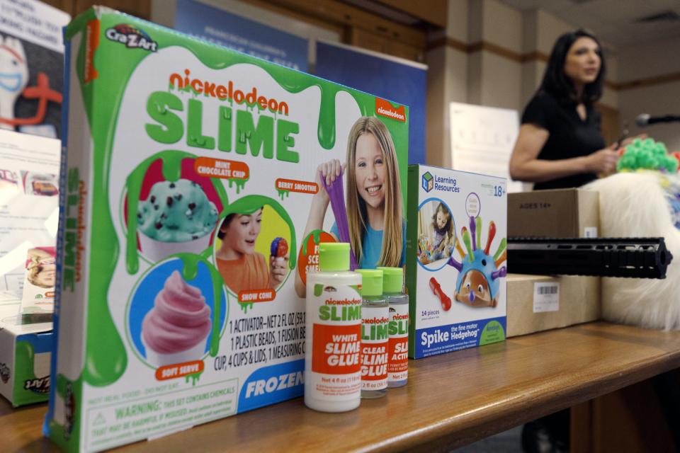 Joan Siff, president of World Against Toys Causing Harm, speaks behind an array of toys, including ice cream-scented Nickelodeon slime, during a news conference in Boston, Tuesday, Nov. 19, 2019. The organization notes that Nickelodeon's Frozen Treats Slime includes mint chocolate chip, berry smoothie, and snow cone-scented versions of the goo even as it warns the products are made of harmful chemicals and shouldn't be eaten. (AP Photo/Michael Dwyer)