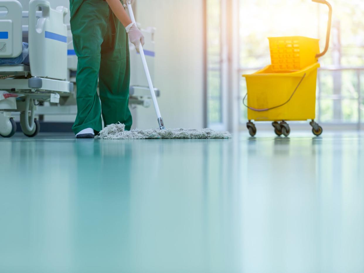 Cleaner using mop to clean hospital floor.