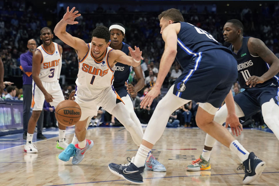 Phoenix Suns guard Devin Booker (1) loses control of the ball after he was fouled by Dallas Mavericks forward Maxi Kleber, right, during the first half of Game 6 of an NBA basketball second-round playoff series, Thursday, May 12, 2022, in Dallas. (AP Photo/Tony Gutierrez)