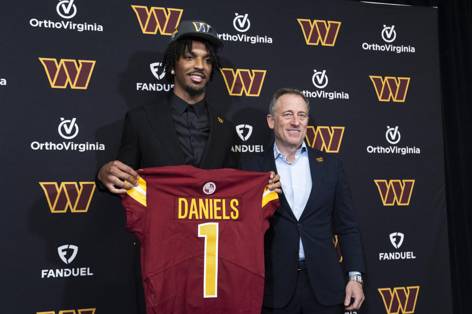 Washington Commanders' first round draft pick Jayden Daniels holds his Commanders jersey as he poses with controlling owner Josh Harris following an NFL football news conference in Ashburn, Va., Friday, April 26, 2024. (AP Photo/Manuel Balce Ceneta)