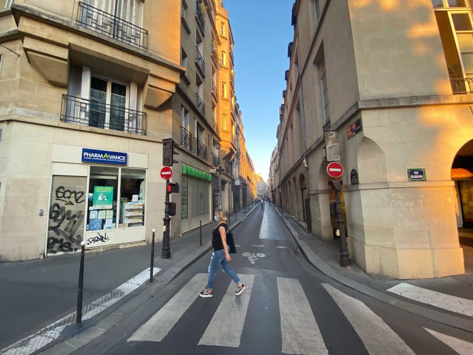 A pregnant woman in the crosswalk crossing the street.