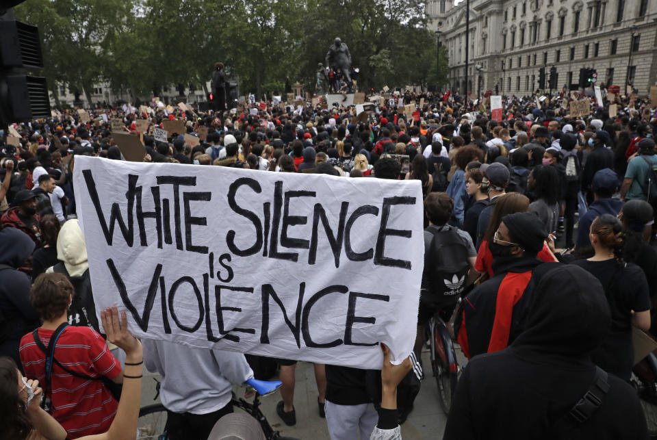 "El silencio blanco es violencia", dice un cartel que muestran manifestantes congregados el 3 de junio del 2020 frente al Parlamento de Londres para protestar la muerte de George Floyd. (AP Photo/Matt Dunham, File)