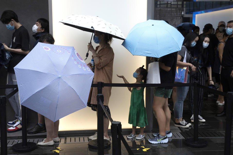 Visitors line up in the rain for the opening of the first Beijing outlet for Shake Shack in Beijing on Wednesday, Aug. 12, 2020. The U.S. headquartered burger chain is opening its first Beijing restaurant at a time when China and the U.S. are at loggerheads over a long list of issues. (AP Photo/Ng Han Guan)