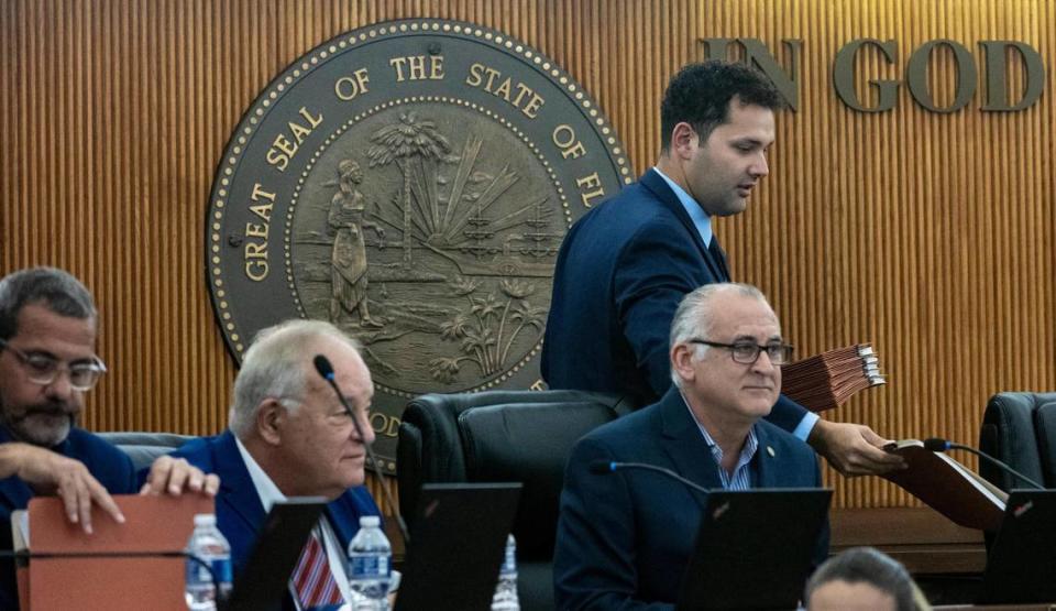 Councilman Bryan Calvo, standing, hands documents to the rest of the councilors, before explaining the reasons why he decided to sue Mayor Esteban Bovo Jr., alleging “systematic abuse of power.” The lawsuit has been dismiss to avoid “interfering in internal decisions”