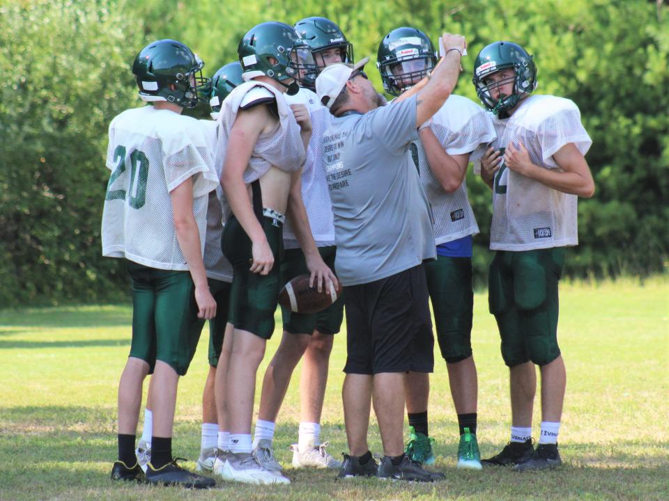 Dighton-Rehoboth head coach Kevin Gousie (center) explains a play to his players during a practice on August 29, 2022.