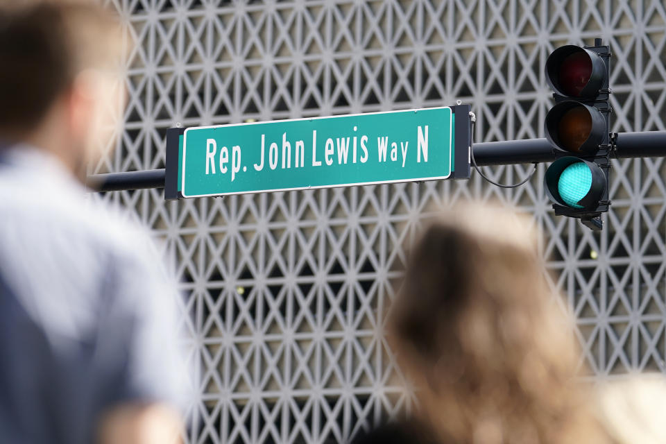 People wait to cross a street that was renamed to honor former Rep. John Lewis Friday, July 16, 2021, in Nashville, Tenn. Nashville leaders on Friday also unveiled a new historical marker remembering Lewis, kicking off a weekend celebrating the civil rights icon. (AP Photo/Mark Humphrey)