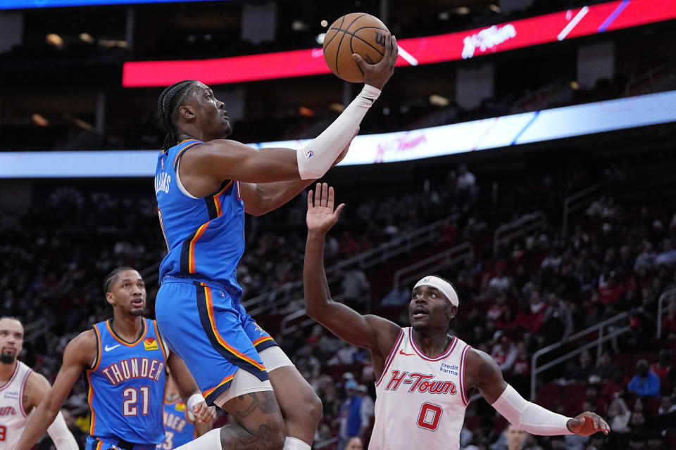 Oklahoma City Thunder forward Jalen Williams (8) drives past Houston Rockets guard Aaron Holiday (0) to score during the first half of an NBA basketball game Wednesday, Dec. 6, 2023, in Houston. (AP Photo/Kevin M. Cox)