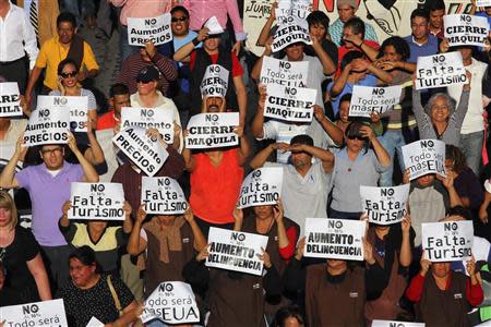 Demonstrators hold up signs during a march against the federal government's economic and tax reforms in Ciudad Juarez October 22, 2013. REUTERS/Jose Luis Gonzalez