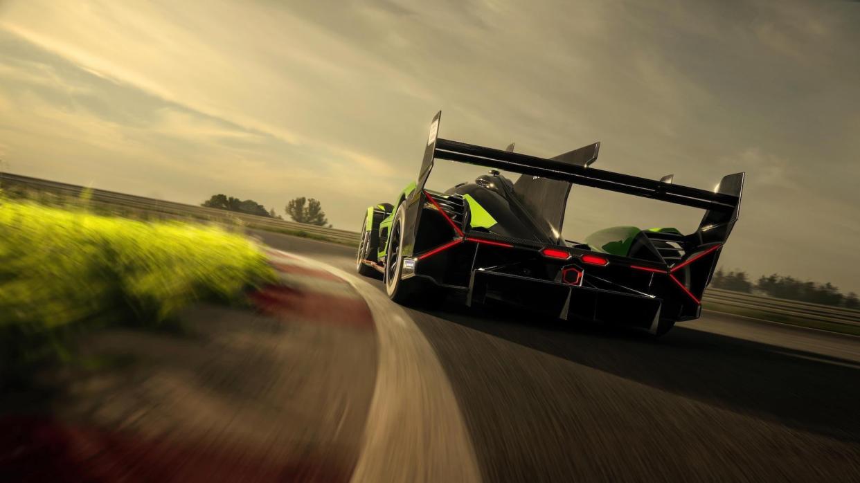 the back end of a black and green race car that is moving on a track