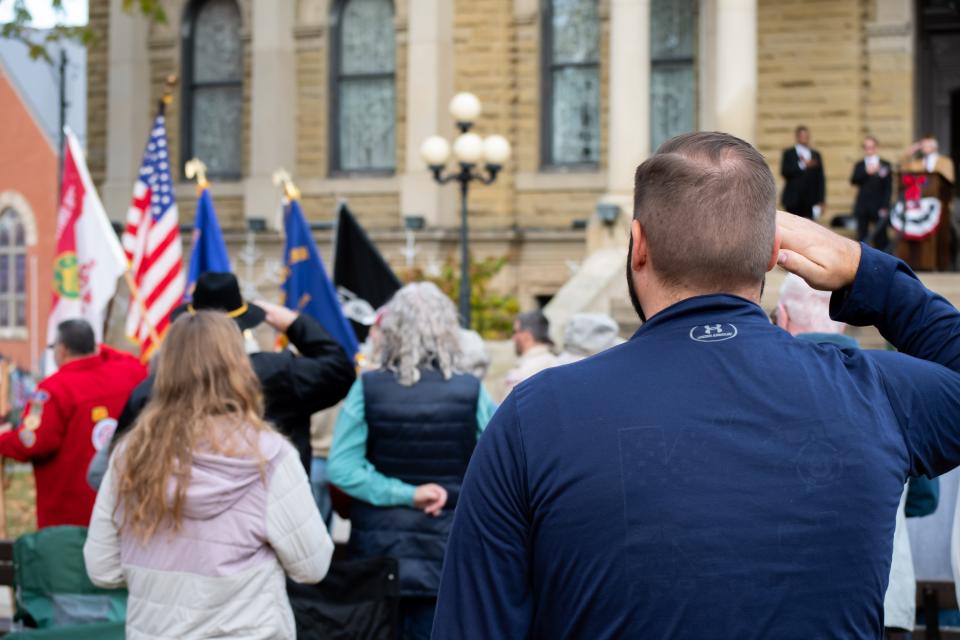 Aaron Coulter (right), a member of the Guernsey County Sheriff's office, salutes during a previous Veterans Day ceremony.