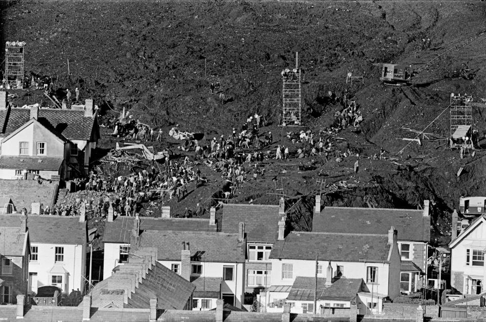 Aberfan, South Wales, circa October 1966: Picture shows the mud and devastation caused when mining spoil from the hillside high above the town behind came down and engulfed The Pantglas Junior School on 21st October 1966. Rescuers trying to find victims and help, amongst the mud and rubble around the school site The Aberfan disaster was a catastrophic collapse of a colliery spoil tip in the Welsh village of Aberfan, near Merthyr Tydfil It was caused by a build-up of water in the accumulated rock and shale, which suddenly started to slide downhill in the form of slurry and engulfed The Pantglas Junior School below, on 21st October 1966, killing 116 children and 28 adults. Picture taken circa 21st October 1966. (Photo by Staff/Mirrorpix/Getty Images)